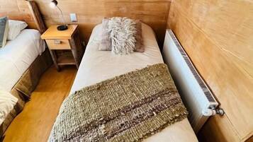 Una habitación acogedora de estilo cabaña con una cama individual, una mesita de noche, una lámpara y un radiador.