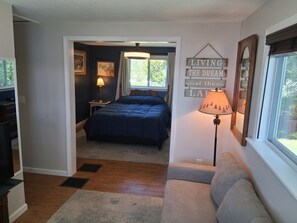 A bedroom with a bed, a nightstand, a lamp, and a wall sign.