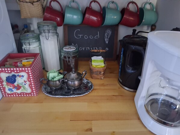 A kitchen counter with various tea-making items, a coffee maker, and a sign that reads 'Good Morning.' - Lakefront Home near Alpena Includes Kayaks, Canoe, Rowboat. Sleeps up to 6 (Alpena)