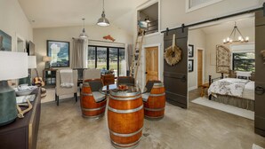 A spacious living area with a high ceiling, a dining table with chairs, and a large window offering a view of the outdoors. - New! Retreat with Hot Tub and Mountain Views near Bozeman! (Gallatin Gateway)