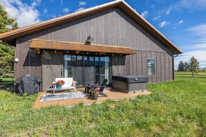 Una casa moderna con patio, mobiliario exterior y bañera de hidromasaje.