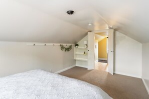 Ein Schlafzimmer mit einem Bett, einem Regal mit Pflanzen und einer Tür zu einem anderen Raum.