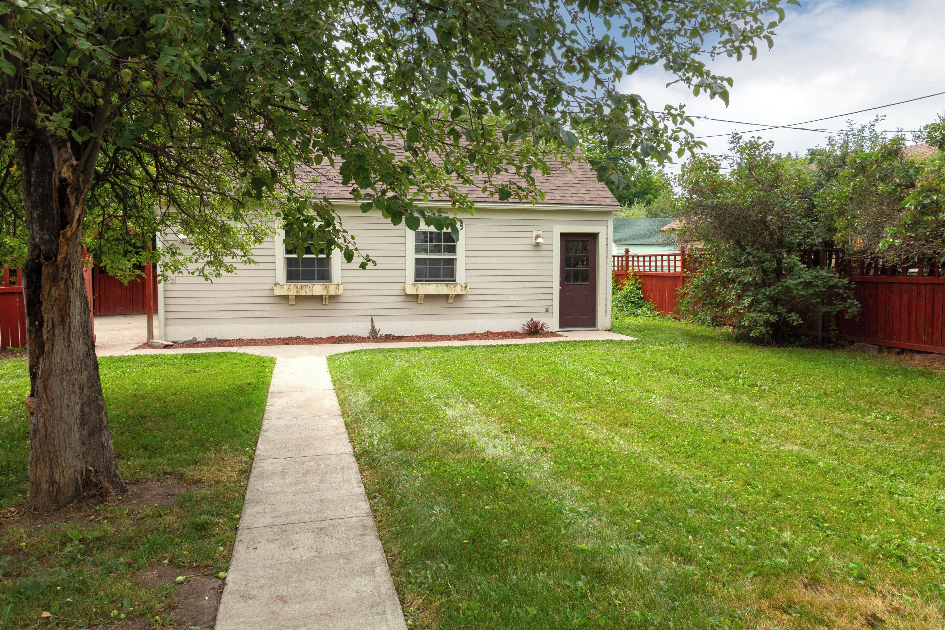 A single-story house with a front yard, a sidewalk leading to the front door, and a red fence surrounding the property.