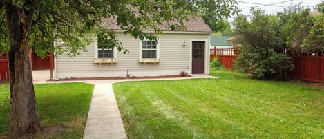 A single-story house with a front yard, a sidewalk leading to the front door, and a red fence surrounding the property.