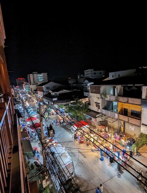 Een nachtelijke blik op een levendige straatmarkt, met diverse kraampjes en gebouwen op de achtergrond.