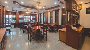 A restaurant with wooden furniture, a bar area, and large windows. - Khampiane Hotel (Vientiane)