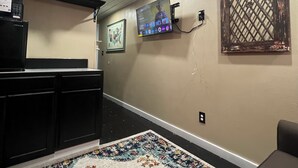 Een kamer met een bed, een aan de muur bevestigde televisie, een bureau met een computer en een kamerbreed tapijt met een patroon.