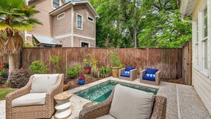 Un patio trasero con piscina, muebles de mimbre y una cerca de madera.