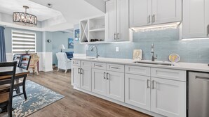A modern kitchen with white cabinets, a stainless steel sink, and a built-in oven. - Updated Direct Oceanfront Condominium with Great Amenities (St. Simons Island)