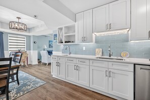 A modern kitchen with white cabinets, a stainless steel sink, and a built-in oven. - Updated Direct Oceanfront Condominium with Great Amenities (St. Simons Island)
