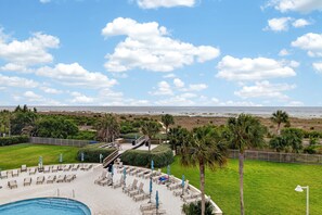 A pool area with lounge chairs and umbrellas, a view of the beach, and a clear sky. - Updated Direct Oceanfront Condominium with Great Amenities (St. Simons Island)