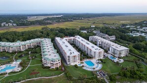 A multi-story hotel with a swimming pool, tennis courts, and a landscaped garden. - Updated Direct Oceanfront Condominium with Great Amenities (St. Simons Island)