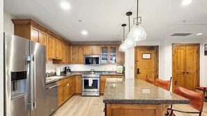 A modern kitchen with wooden cabinets, stainless steel appliances, granite countertops, and pendant lighting. - NEW LISTING | Beautiful Lodge at Mountaineer Square 2 Bedroom (Crested Butte)