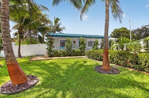 A house with a green roof, surrounded by a well-maintained lawn and palm trees. - BEACH HOME (Boynton Beach)