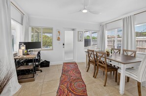 A modern kitchen with a dining area, a computer desk, and a colorful rug. - BEACH HOME (Boynton Beach)