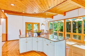 Una cocina espaciosa con una isla grande, techo de madera y ventanas amplias.
