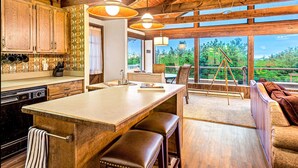 Una cocina con armarios de madera, una isla grande y una zona de comedor con vistas al exterior.