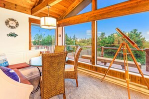 A wooden deck with a telescope, a wicker chair, a bench, and a table with a lamp.