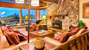 Una sala de estar acogedora con sofás de cuero, una chimenea de piedra y ventanas amplias que ofrecen una vista.