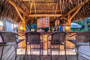 A tiki bar with a thatched roof, wooden bar counter, and three wicker chairs. - Heated Pool/Hot Tub/10 min Beach & Airport (Fort Lauderdale)