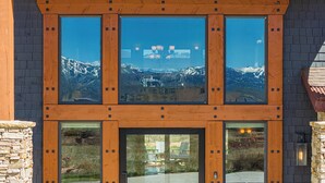 Ein Gebäude mit einer Stein-Fassade, großen Fenstern und Blick auf Berge.