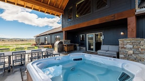 Ein Whirlpool mit Holzterrasse, Sitzgelegenheit im Freien und einer Steinmauer.