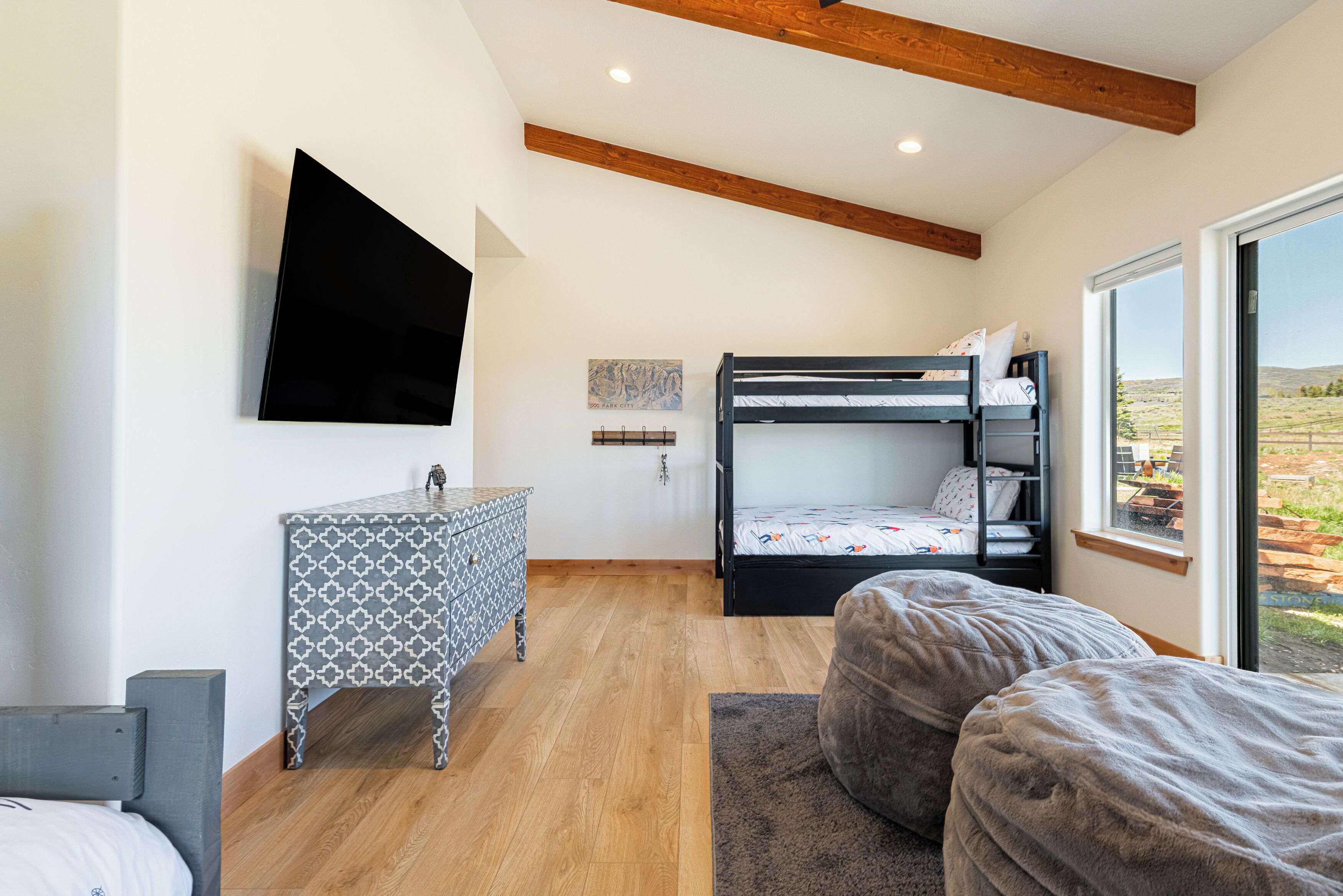 Une chambre avec un lit superposé, un bureau, un téléviseur fixé au mur et une fenêtre donnant sur l’extérieur.