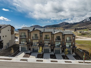 A row of modern multi-story residential buildings with large windows and balconies, set against a mountainous backdrop. - Adventure Awaits-Hike, Bike, Ski & Water Sports All Just Minutes Away (Heber City)