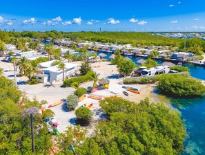 Un resort costero con varias cabañas, un puerto deportivo y una zona de playa con kayaks.
