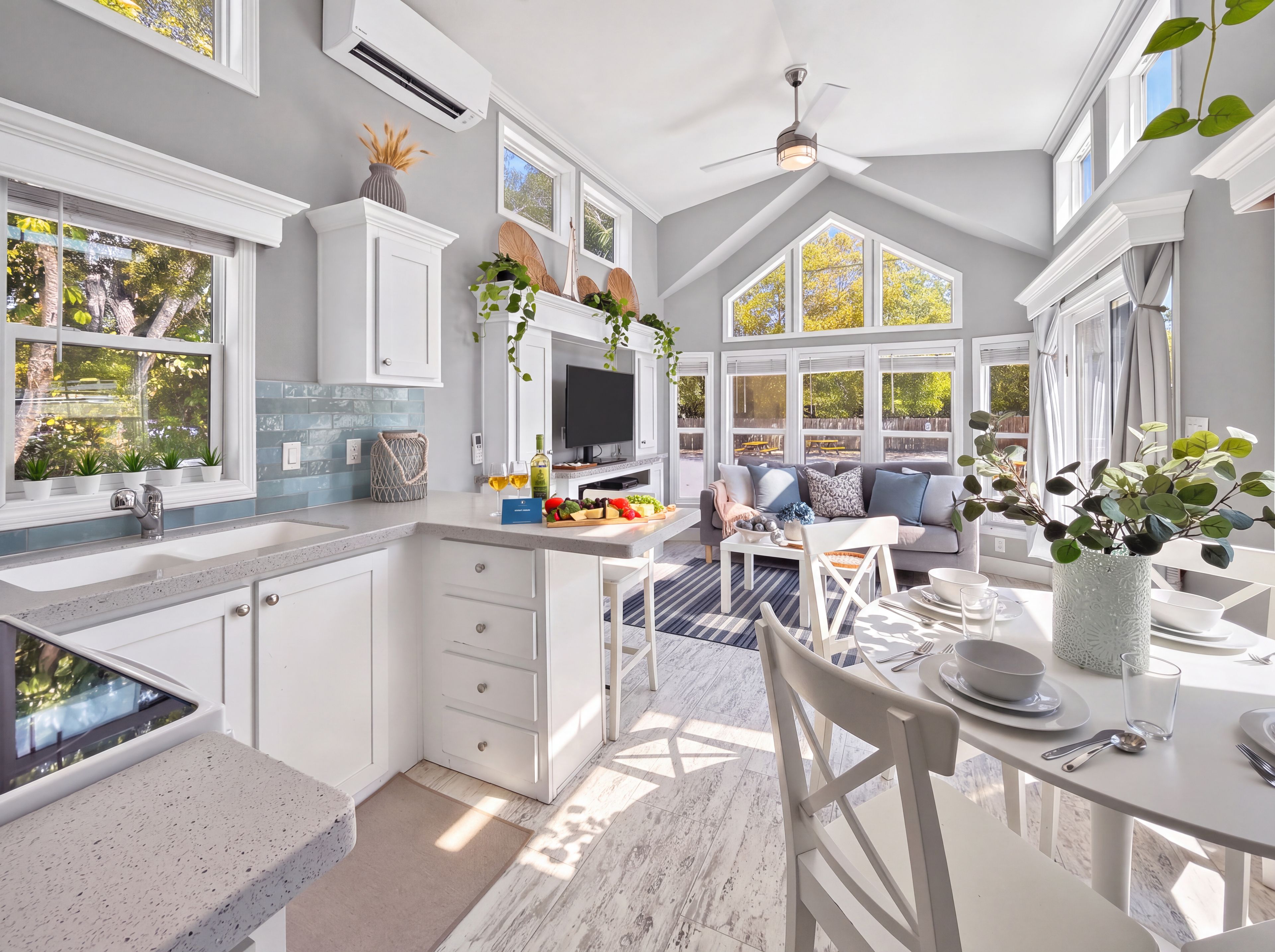 Eine moderne Küche mit Essbereich, großen Fenstern und einem Deckenventilator.