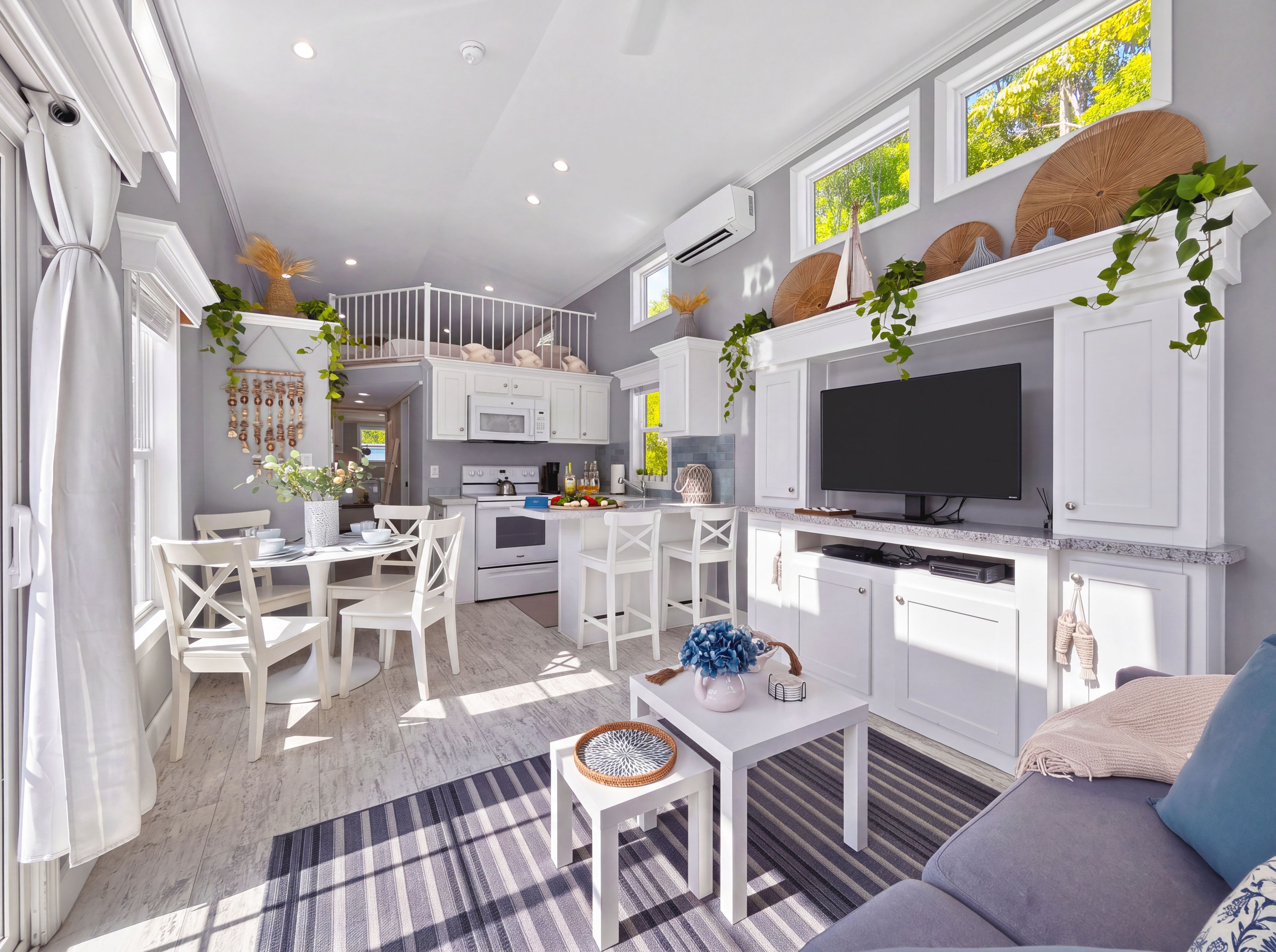 A modern kitchen with white cabinetry, a built-in oven, and a flat-screen TV.