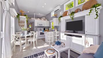 A modern kitchen with white cabinetry, a built-in oven, and a flat-screen TV.