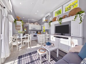A modern kitchen with white cabinetry, a built-in oven, and a flat-screen TV. - New Tiny Home-Paddle Boards, Kayaks, Pool, Marina (Key Largo)