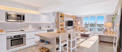 A modern kitchen with built-in appliances, a dining area with a central island, and a living space with a city view.
