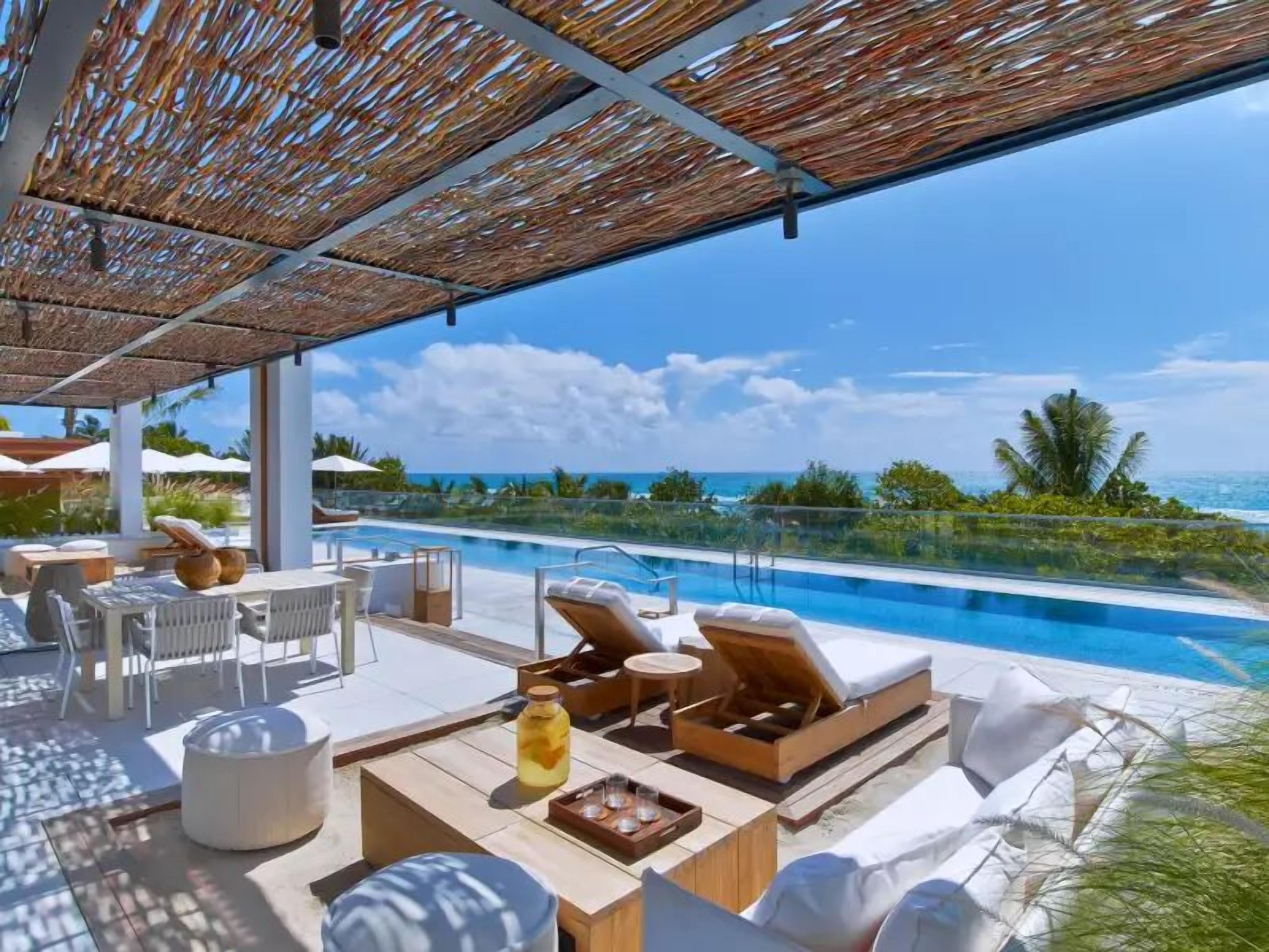 Un espace aménagé au bord de la piscine, avec des chaises longues, une table et une bouteille de boisson.