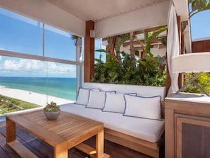 A wooden deck with a sofa and table, a potted plant, and a view of the beach. - 1 Hotel South Beach-Oceanview Balcony-Resort Amenities (Miami Beach)