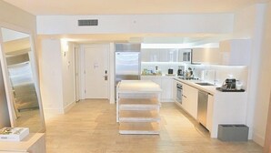 Una cucina moderna con mobili bianchi, forno integrato e un piano di lavoro con macchina da caffè.