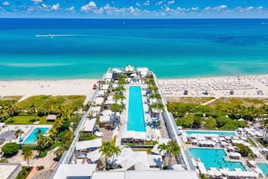 Un complexe hôtelier doté d’une piscine centrale, de plusieurs petites piscines et d’une zone de plage.