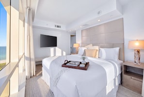 A modern hotel room with a large bed, a flat-screen TV mounted on the wall, and a view of the sea. - 1 Hotel South Beach | 2BR, 14th FL Balcony, water view (Miami Beach)