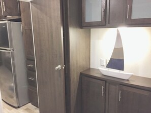 Una cocina con armarios de madera oscura, un refrigerador de acero inoxidable y una mesa blanca con un modelo decorativo de velero.
