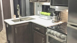 A modern kitchen with dark wood cabinets, stainless steel appliances, a built-in oven, and a sink. - 2 BR/2 BA Oasis Kayaks, Pool, Beach & Dock Rental (Key Largo)