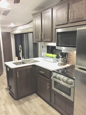 Una cocina moderna con armarios de madera oscura, electrodomésticos de acero inoxidable y encimera blanca.