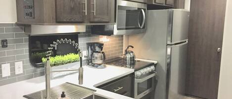 A modern kitchen with dark wooden cabinets, stainless steel appliances, a built-in microwave, and a stainless steel refrigerator.