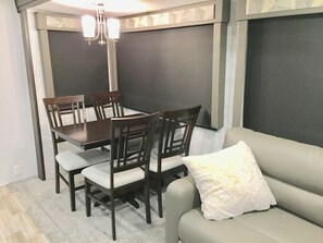 Un comedor con una mesa y sillas, un sofá con un cojín, y una lámpara en el techo.