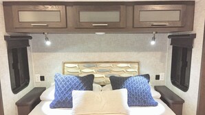 A bed with a headboard, two pillows, bedside tables, and a wall-mounted light fixture. - 2 BR/2 BA Oasis Kayaks, Pool, Beach & Dock Rental (Key Largo)