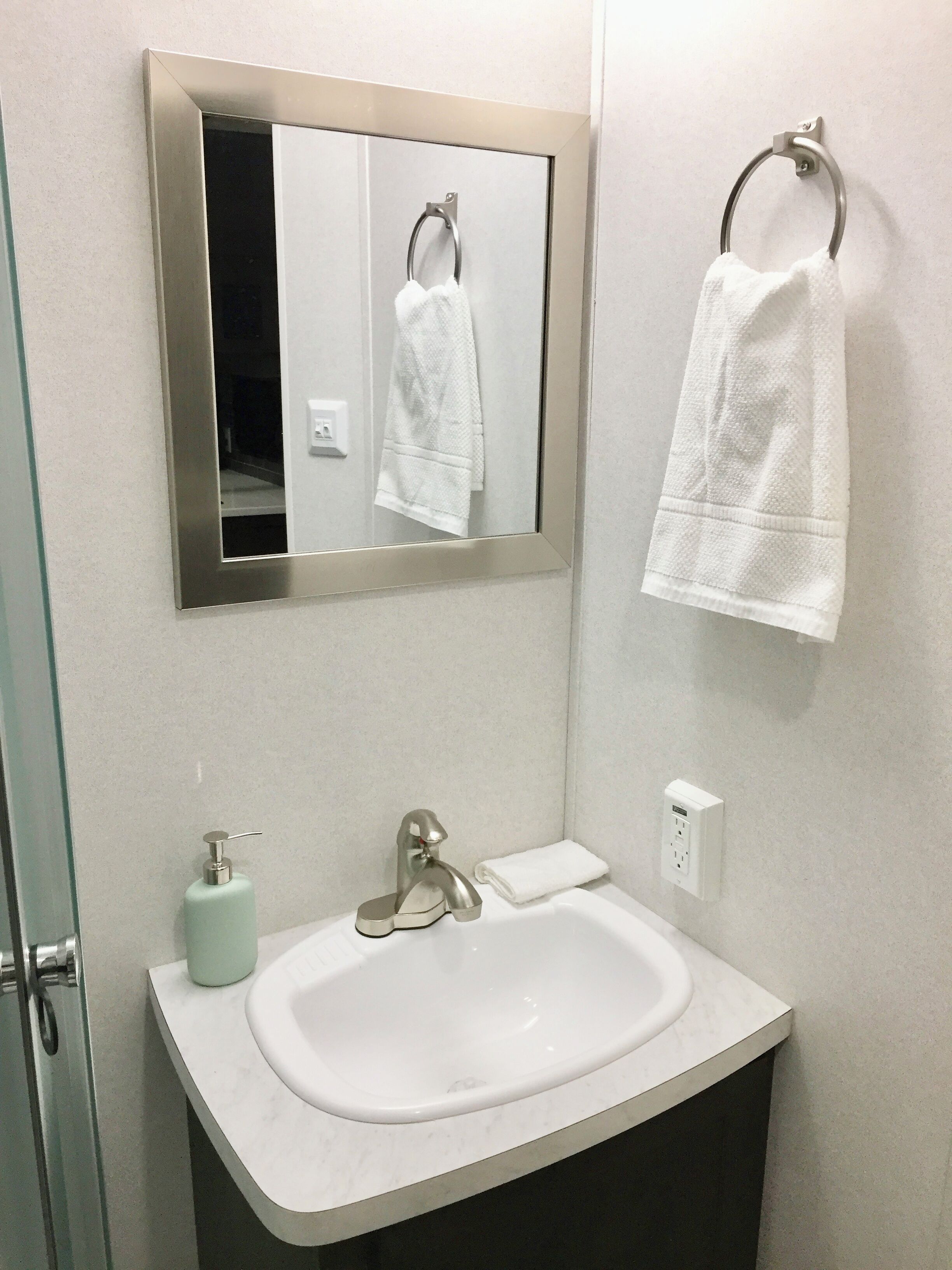 Une salle de bain avec un lavabo blanc, un miroir et un porte-serviettes.