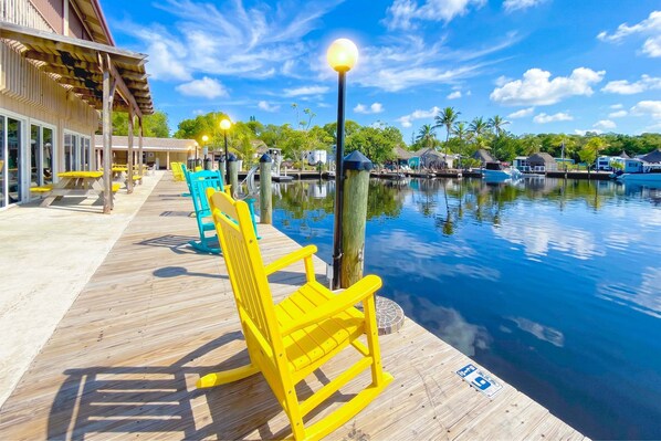 A wooden deck with yellow chairs, a pool, and a building with a covered area.