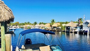 A boat docked at a marina with a thatched-roof structure nearby. - Waterfront Tiny Home w/ Pool, Beach, Dock, Kayaks (Key Largo)