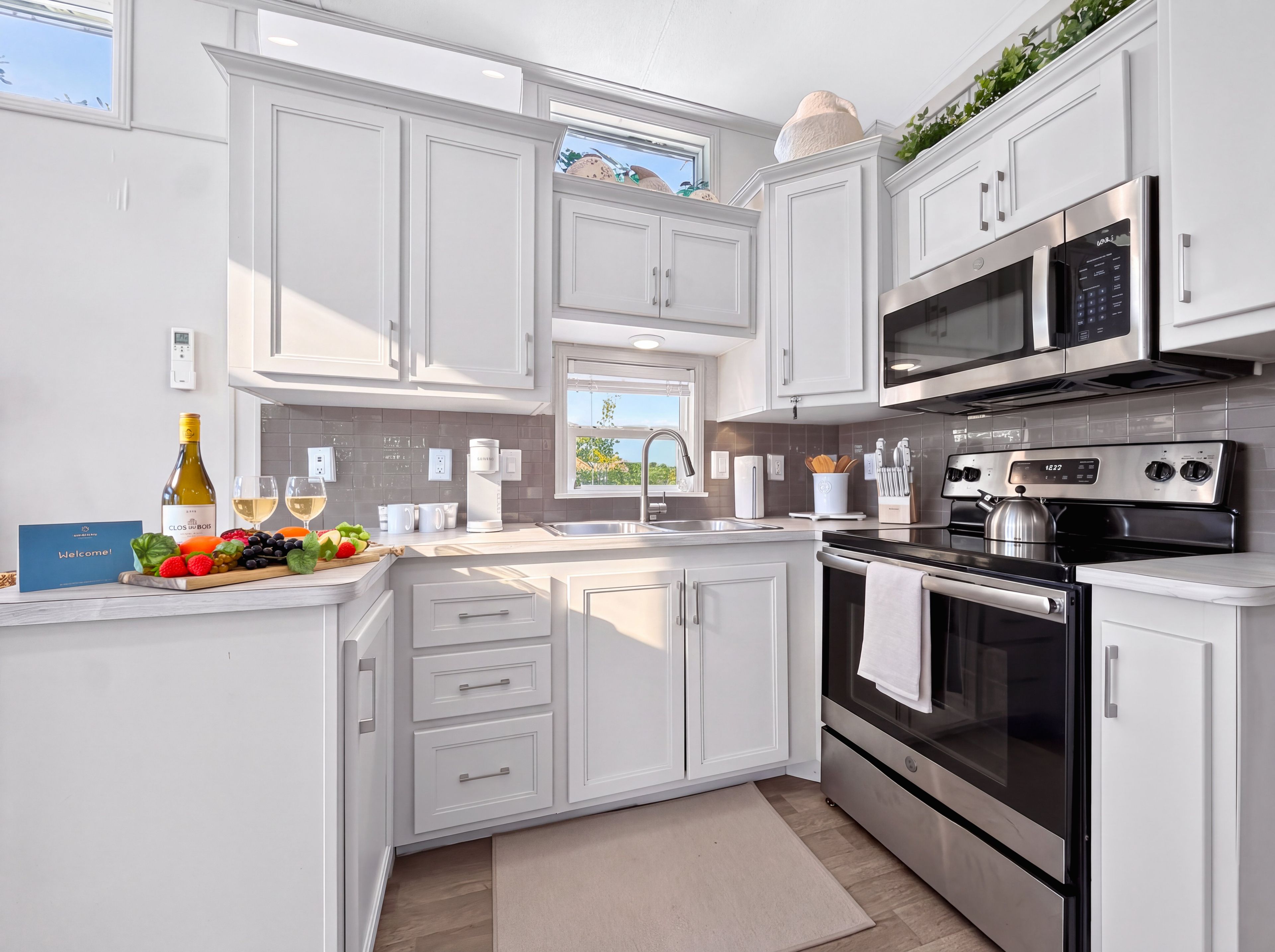 A modern kitchen with white cabinetry, stainless steel appliances, and a breakfast bar.