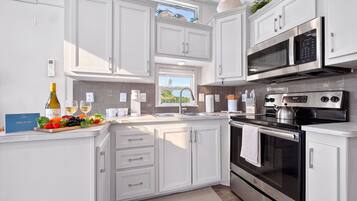 A modern kitchen with white cabinetry, stainless steel appliances, and a breakfast bar.